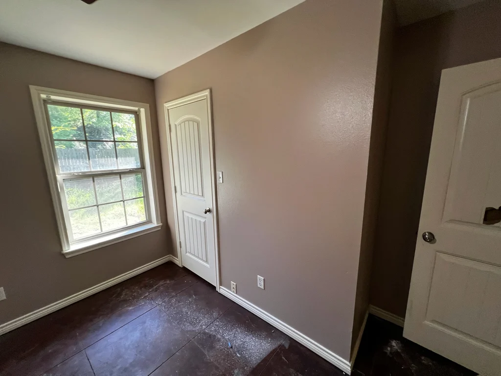 Finished room after repair and painting, taupe walls, white panelled door and window trim