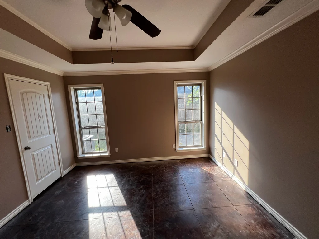 Repainted bedroom with tray ceiling, two windows and sunlight falling across dark tile