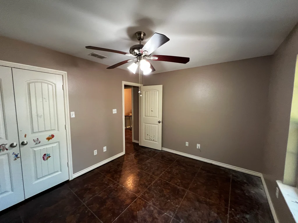 Finished taupe room with two white panelled doors, ceiling fan and polished dark tile