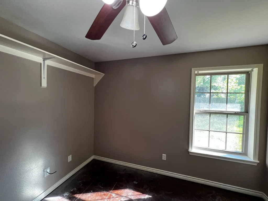 Bright finished room, taupe walls, white shelf and trim, window onto green garden