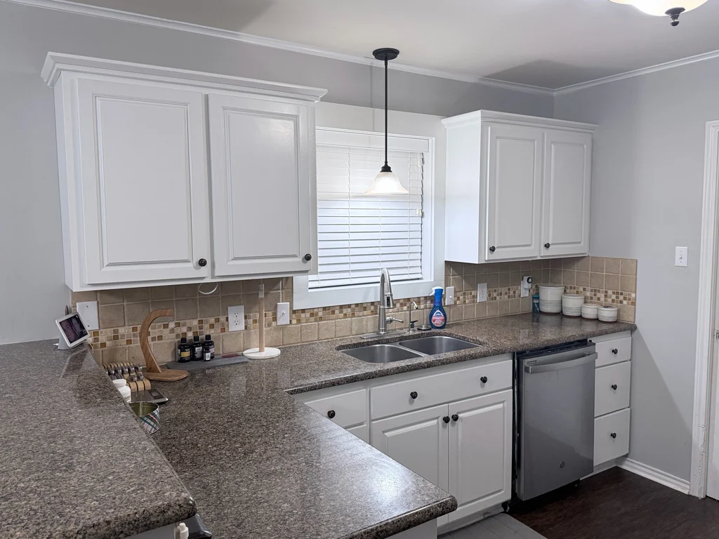 After view of the cabinet repaint, white doors and drawers against gray walls and granite