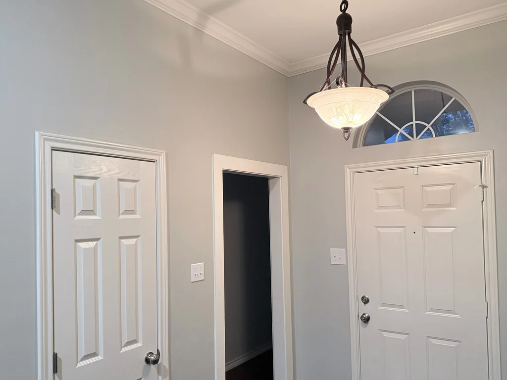 Matched after view of the entry, gray walls and white doors beneath the arched transom