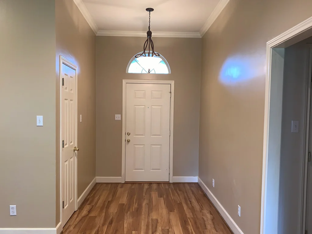 Matched before view of the entry, tan walls and ceiling above a wood plank floor