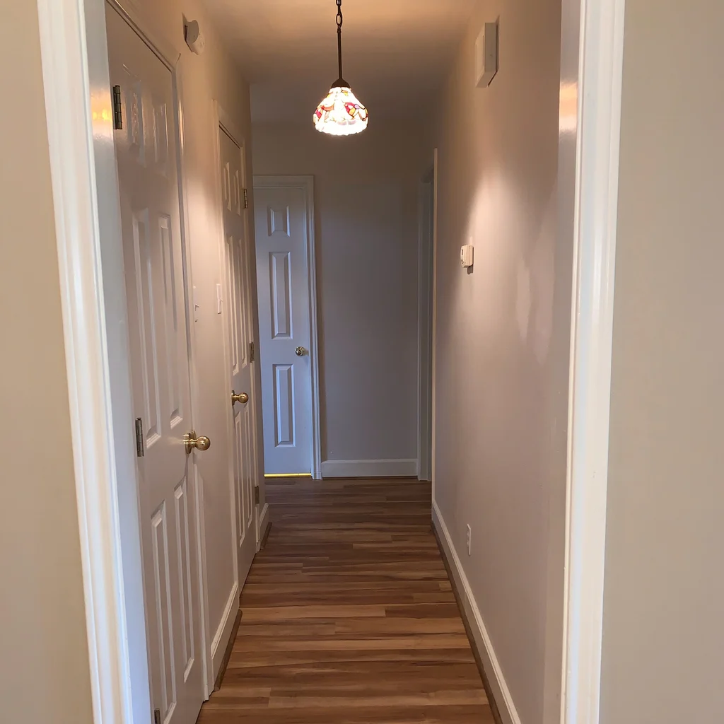 Matched before view of the hallway, warm tan walls and trim over a honey oak plank floor