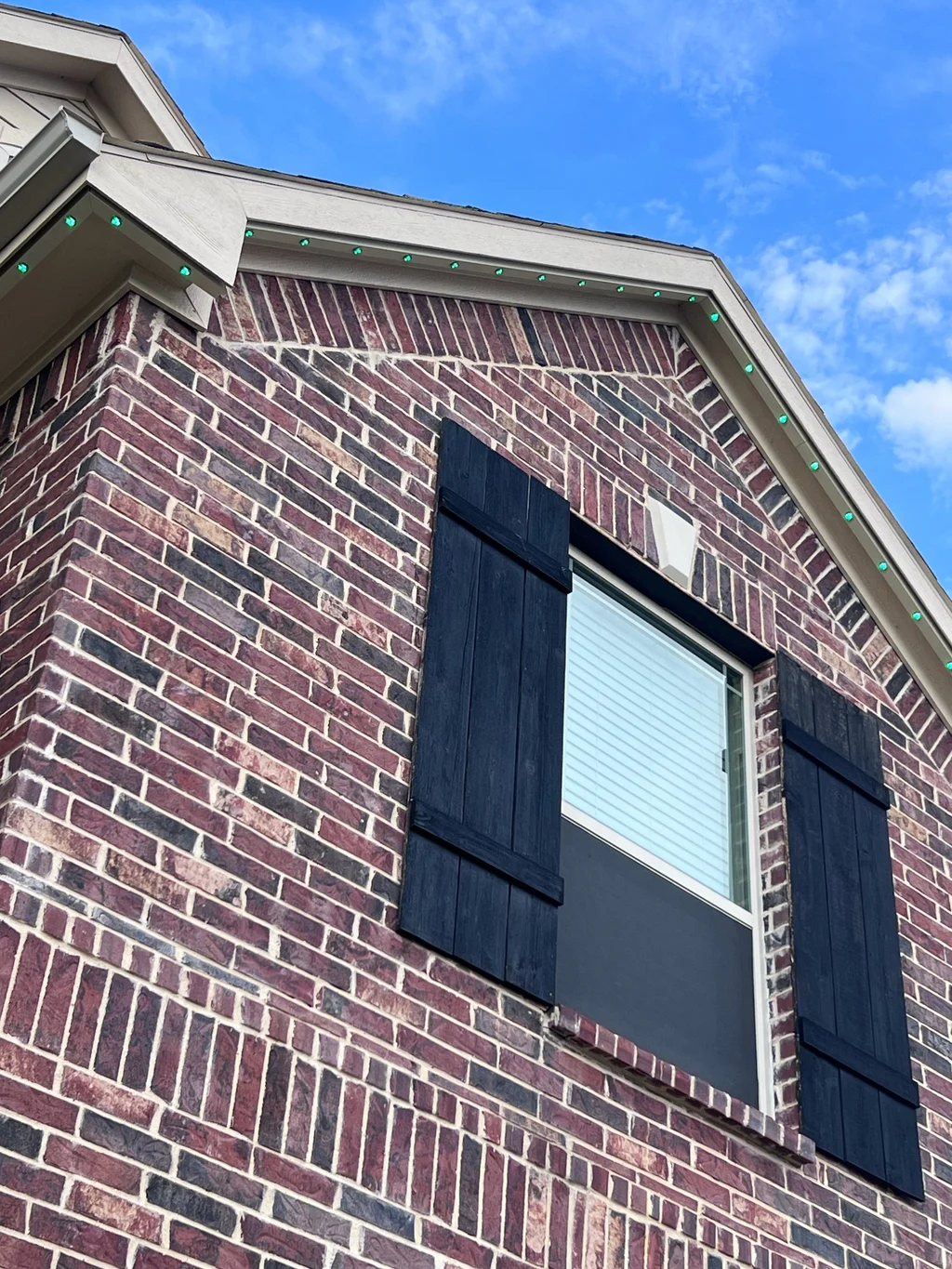 Cream soffit and gable rake on red brick fitted with lighting track, blue sky behind