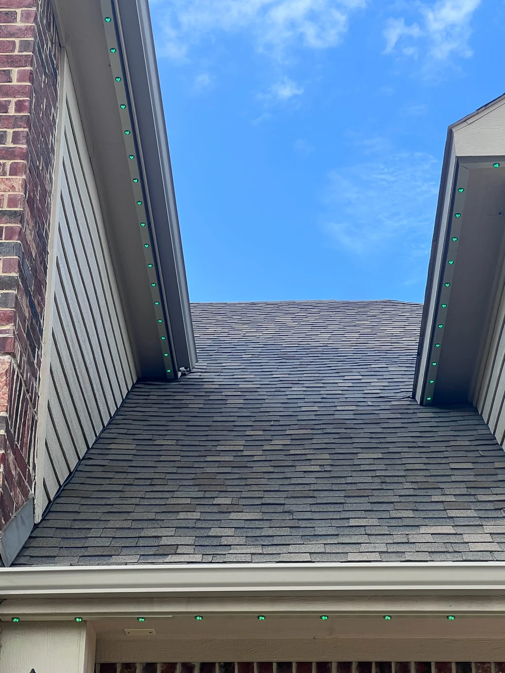 Lighting track along two facing gables above a shingled roof valley in daylight