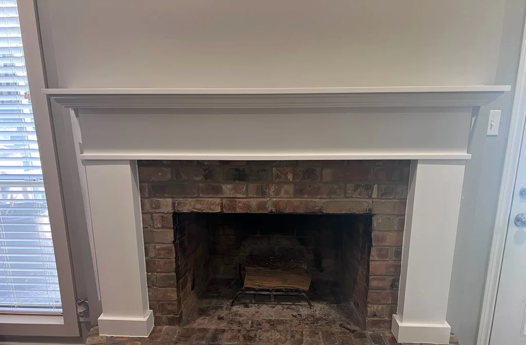 Fireplace mantel and surround painted white above the original brick firebox and raised hearth